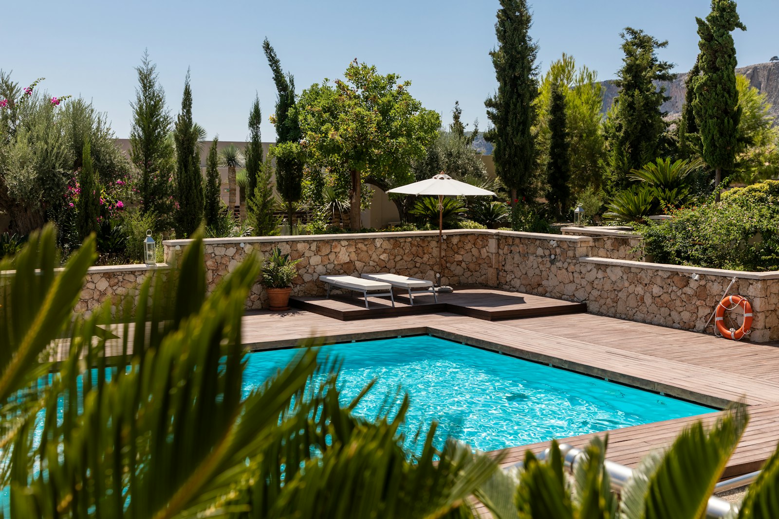 Crystal-clear sparkling backyard pool with stone deck and lounge chairs after a full rescue service