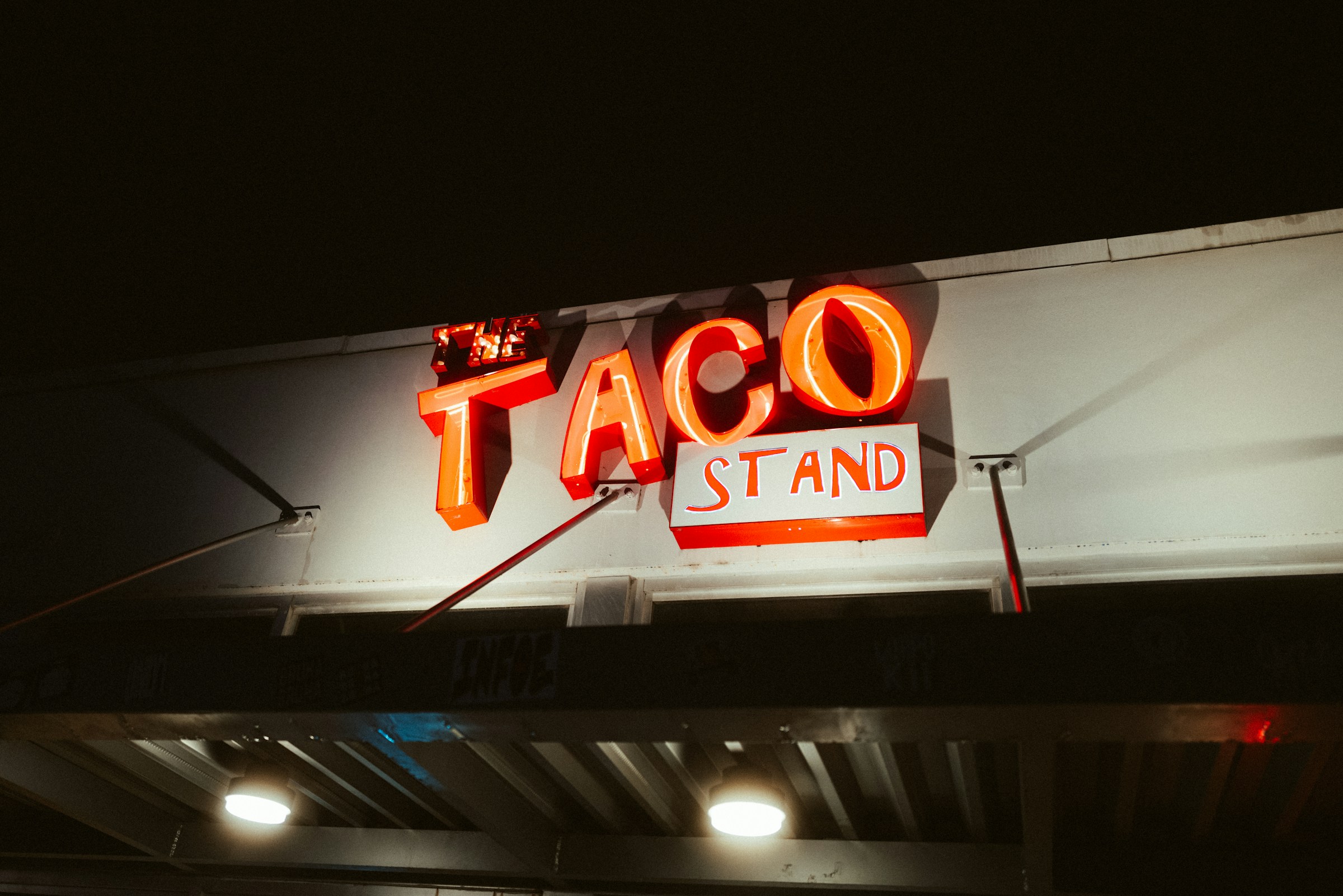 A taqueria sign lit up at night.