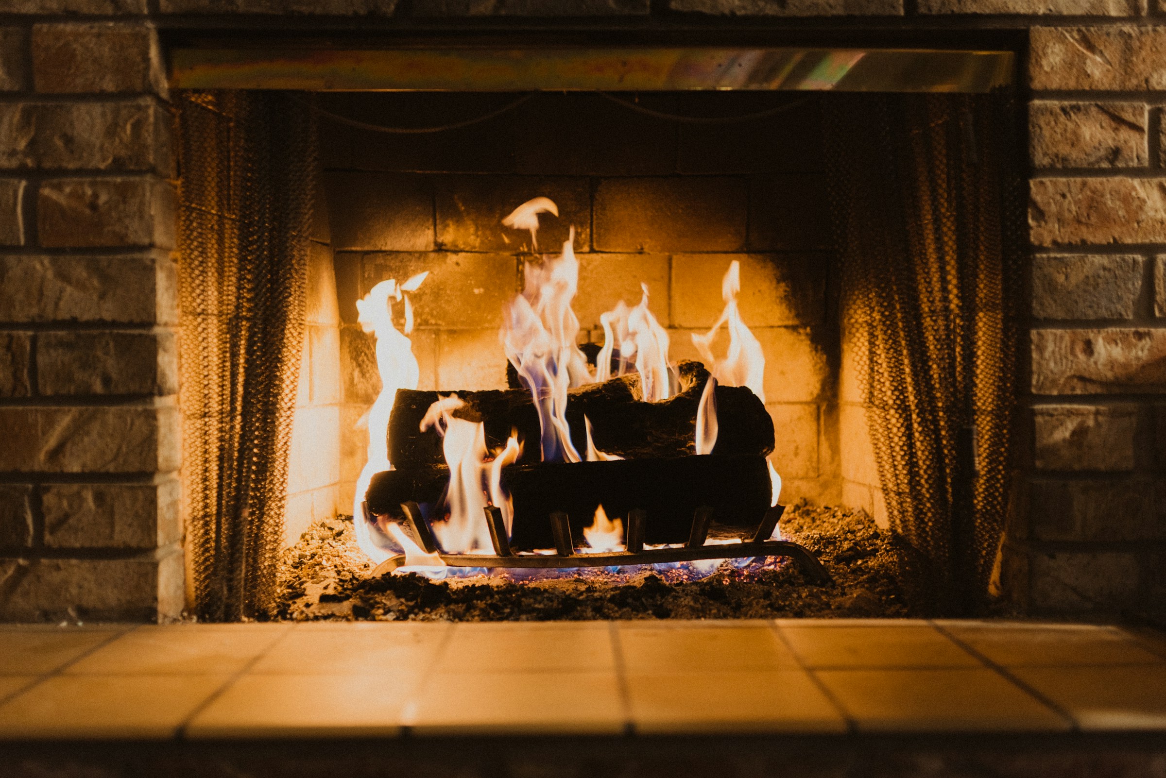 Split oak and hardwood logs stacked over open flame.