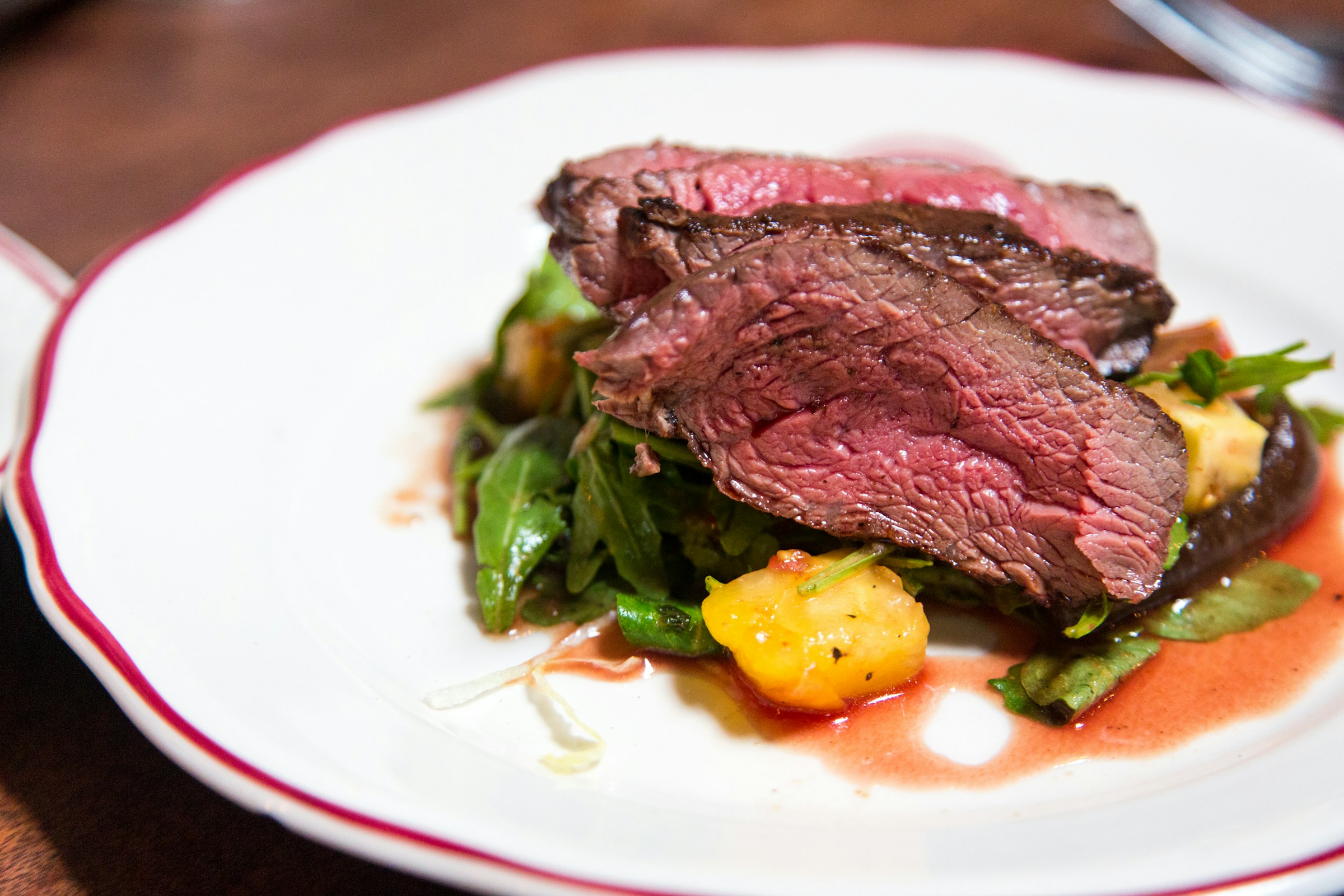 Seared medallion of beef on a dark ceramic plate.