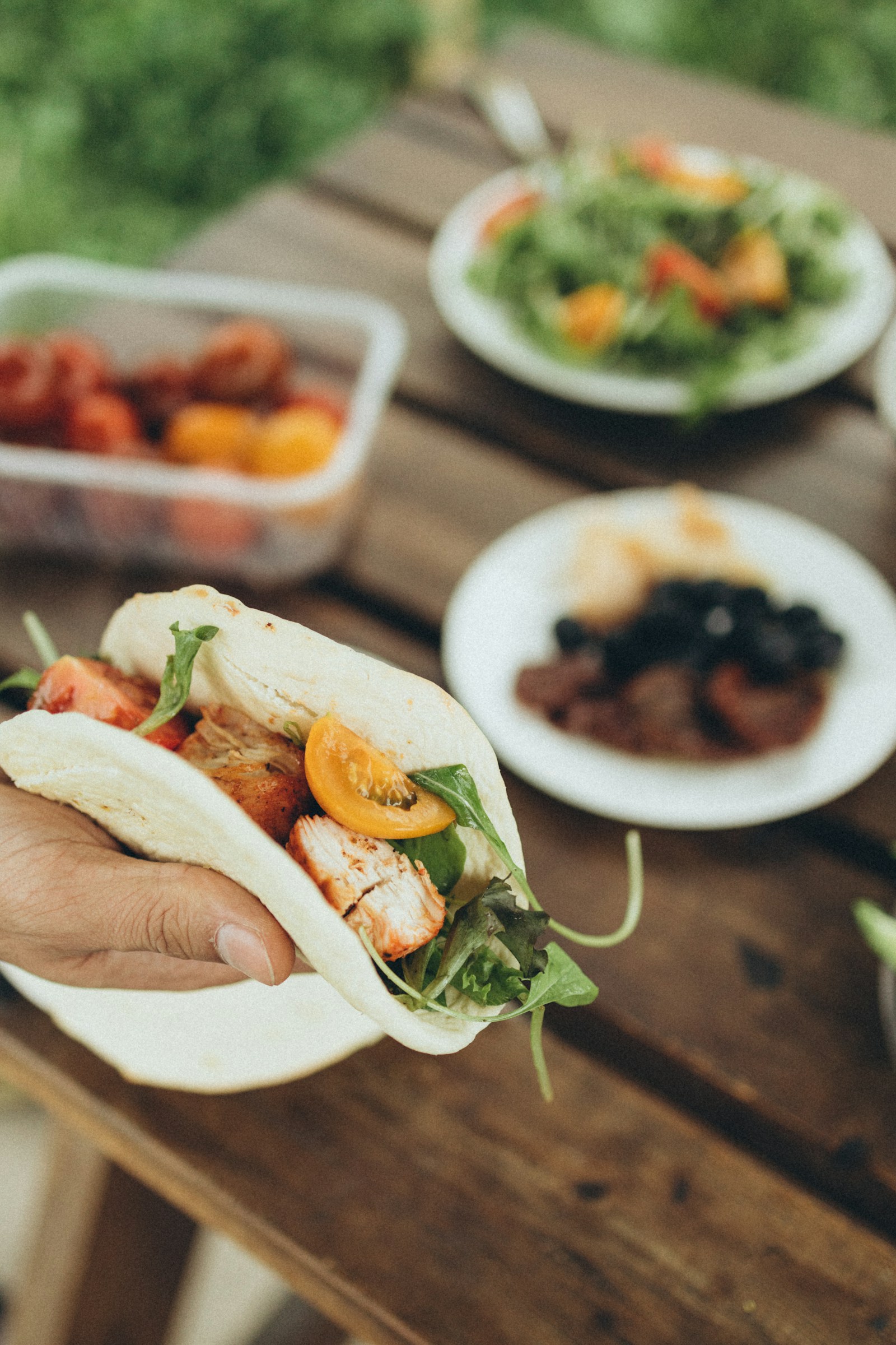 A half-eaten street taco held in one hand over a paper wrapper