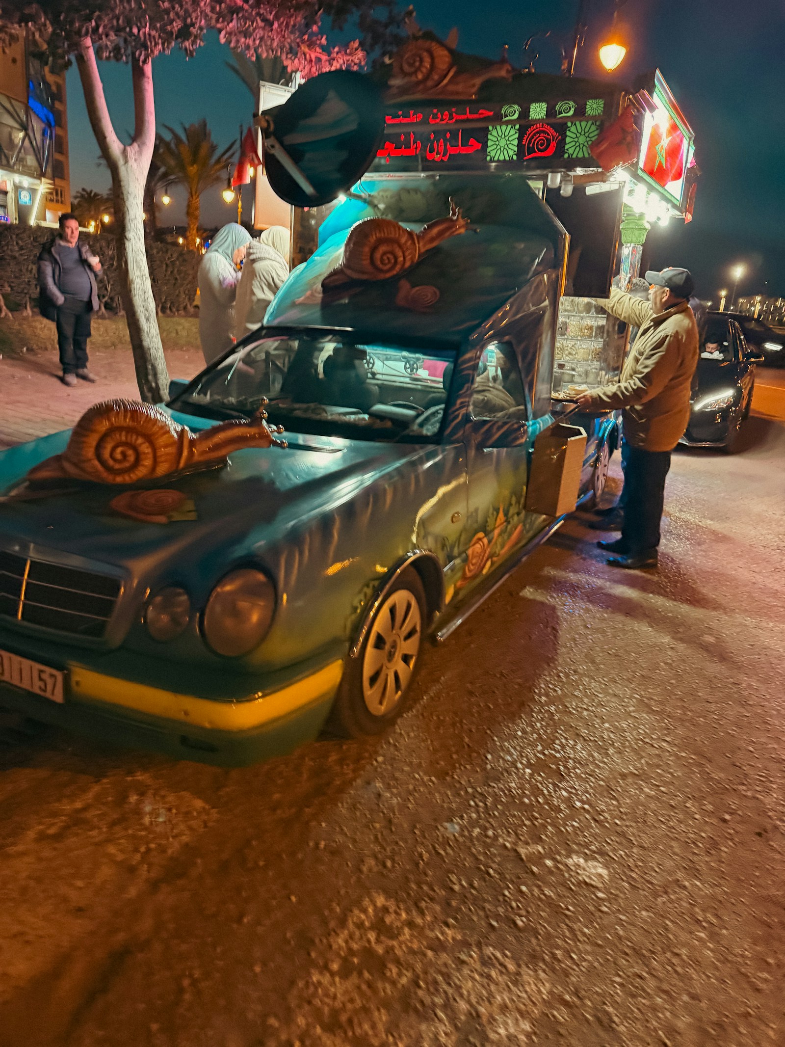 A lit food truck service window at night with a customer waiting