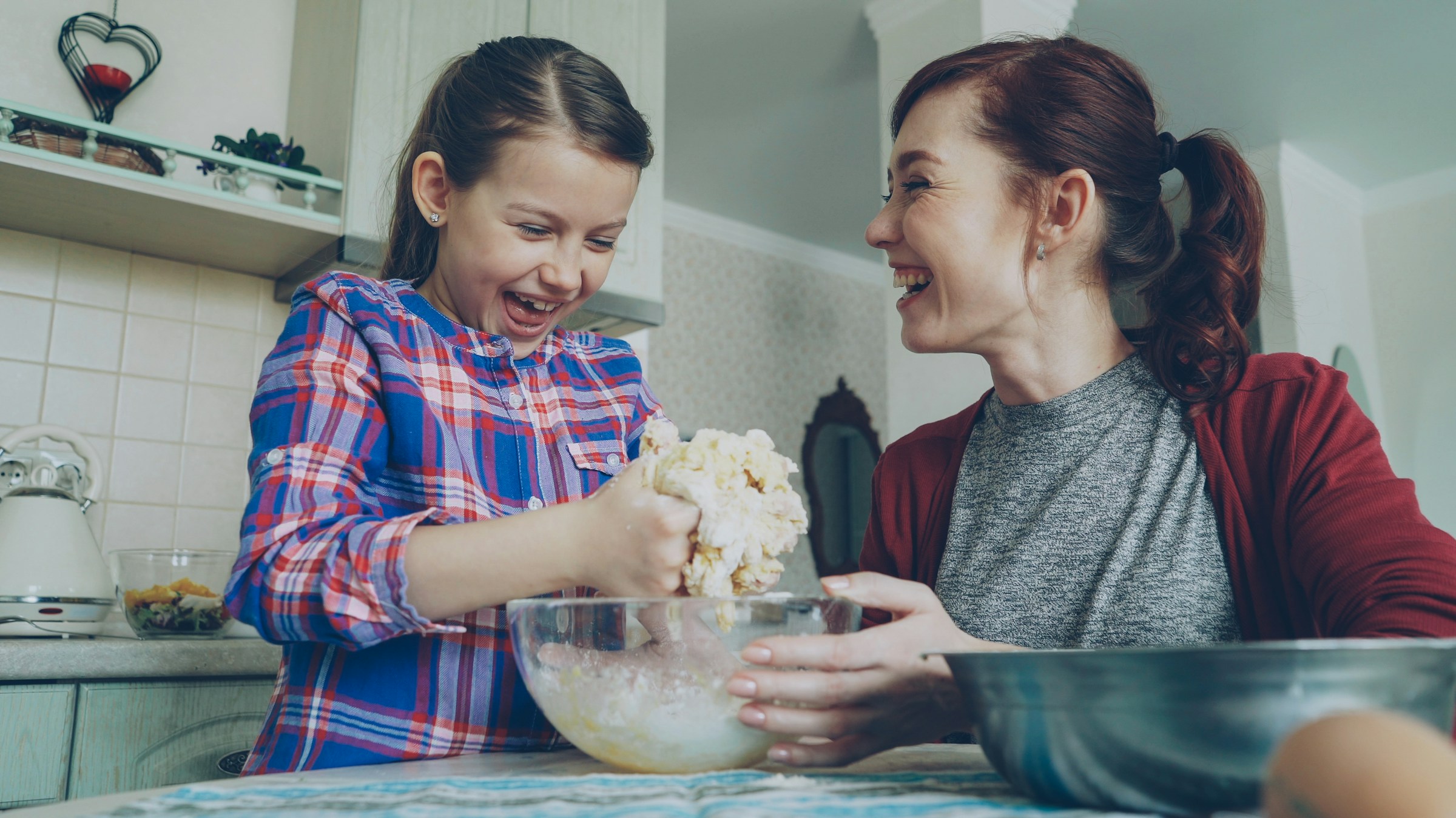 Two people baking together in a home kitchen, laughing over the counter.